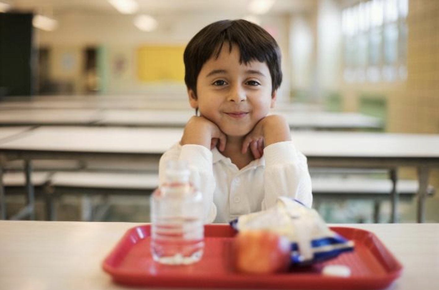 young boy smiling with school lunch