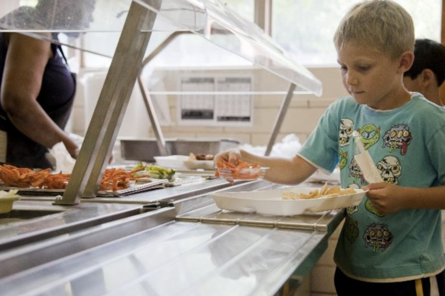 young boy getting school lunch in cafeteria