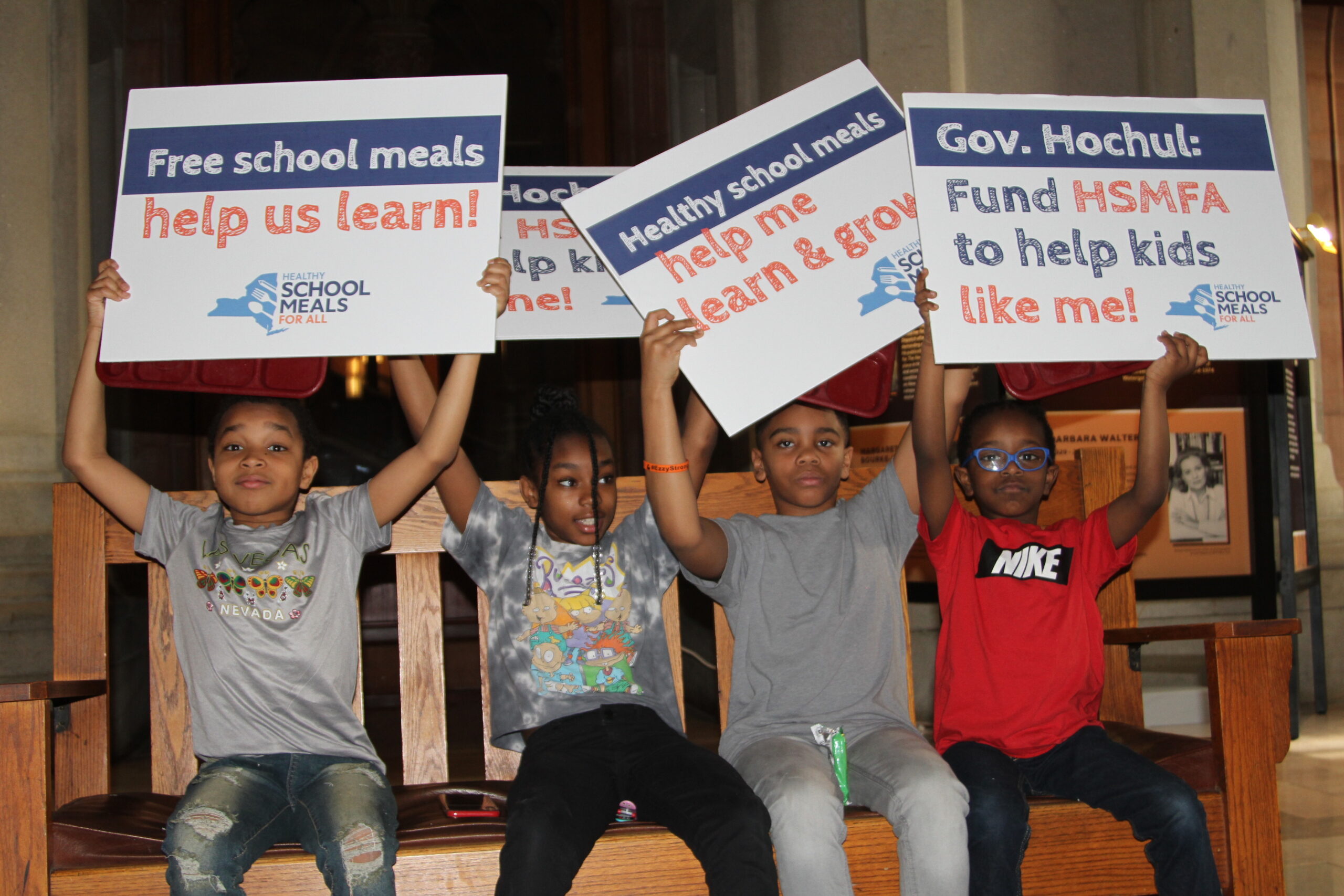 children with 'fund school meals' signs