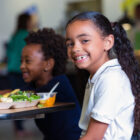 elementary school girl eating healthy lunch in school cafeteria