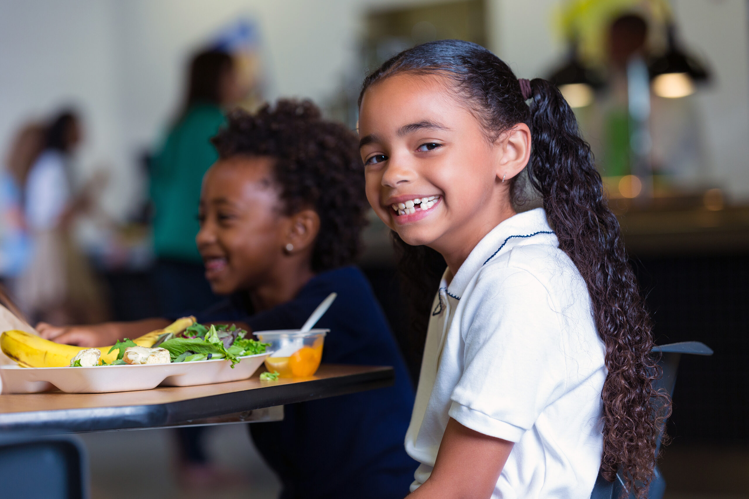 elementary school girl eating healthy lunch in school cafeteria