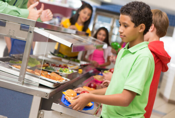 Middle school students getting lunch items in cafeteria line.