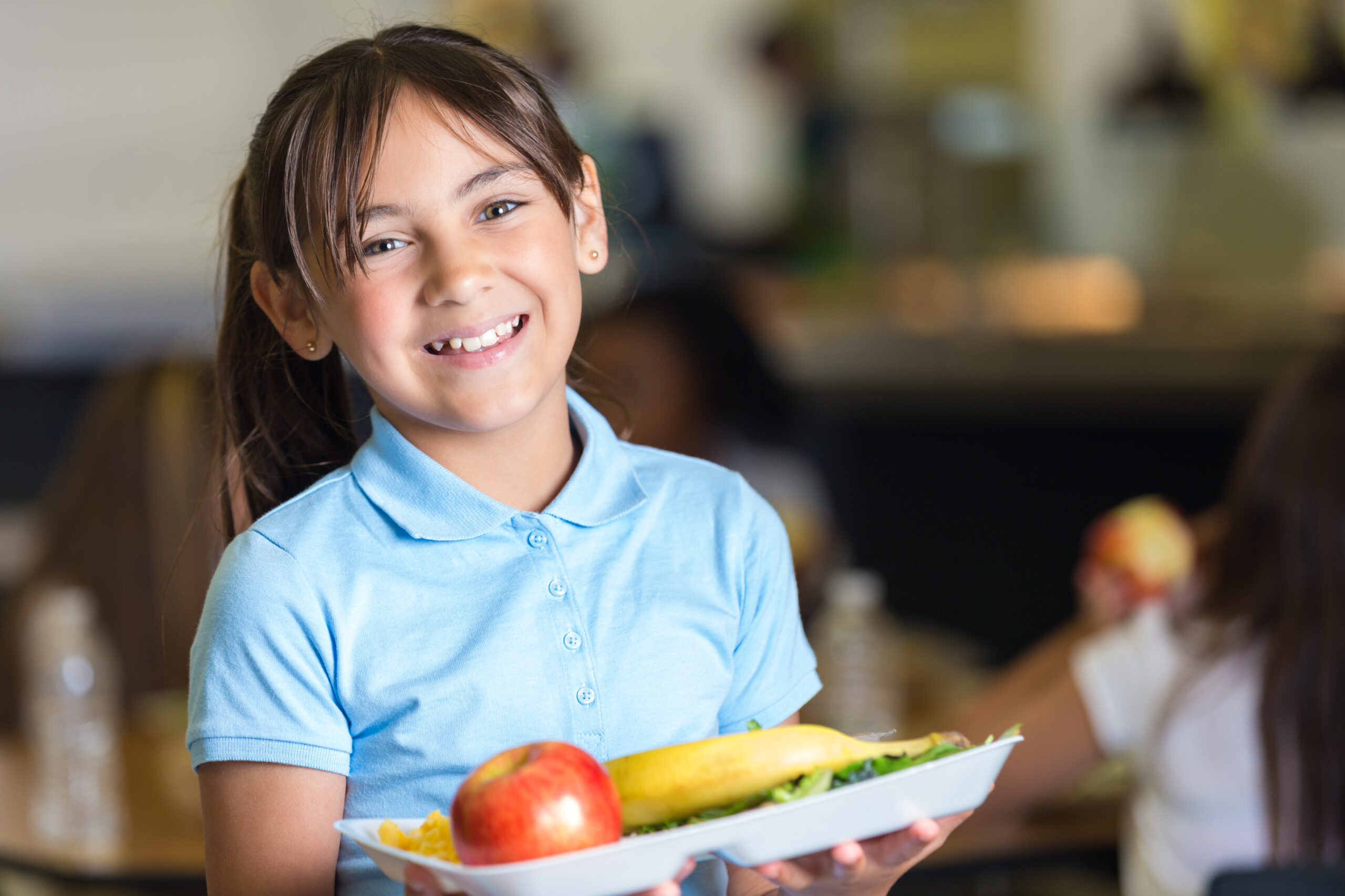 elementary school student holding tray of food in lunchroom