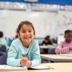 A cute little girl works in her math workbook.