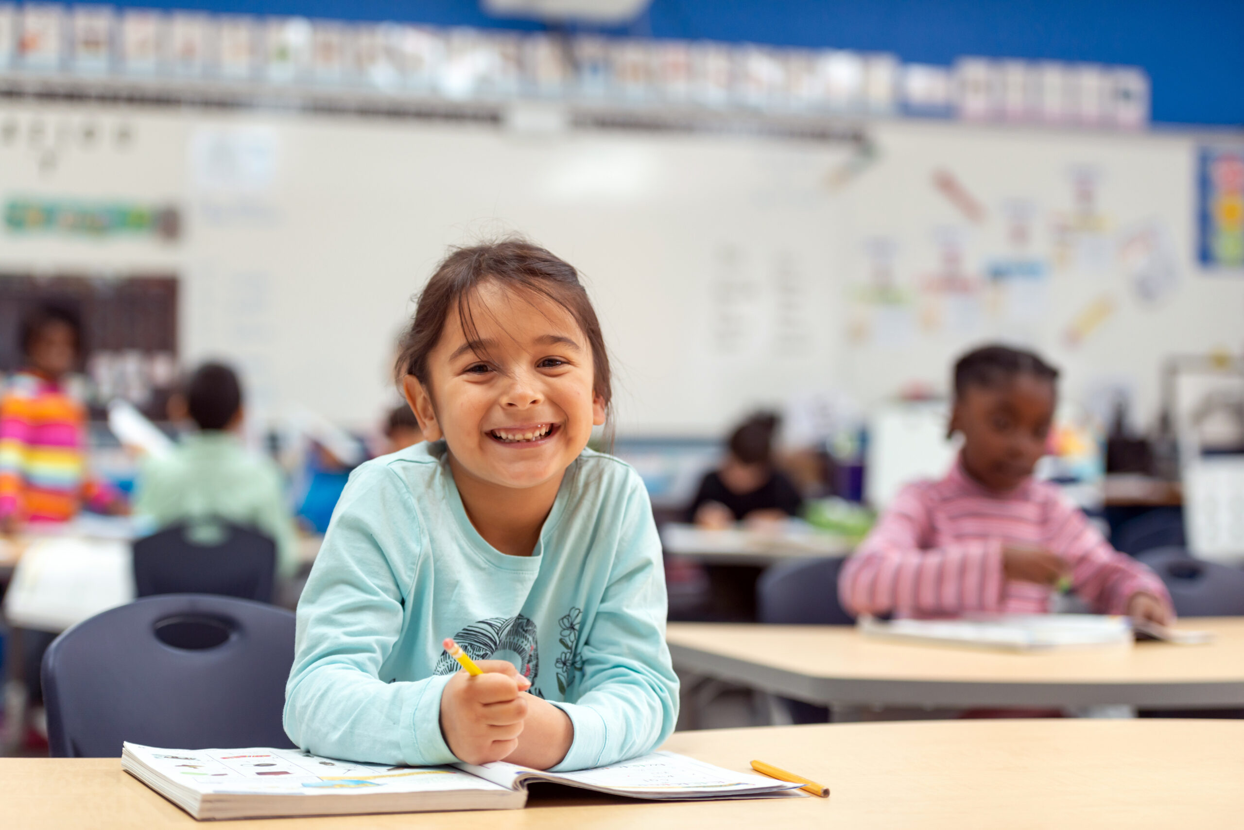 A cute little girl works in her math workbook.